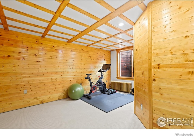 exercise area with carpet floors, wood walls, and radiator heating unit