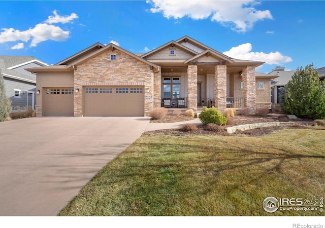 craftsman house with a porch, an attached garage, brick siding, driveway, and a front yard