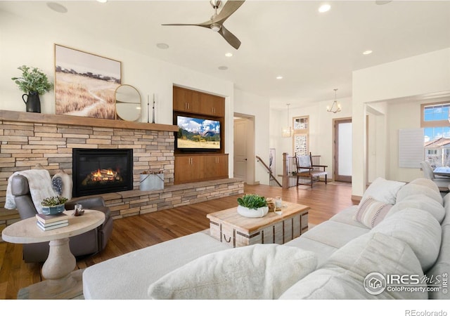 living room with recessed lighting, ceiling fan, a stone fireplace, and wood finished floors