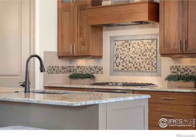 kitchen featuring brown cabinets, premium range hood, and a sink