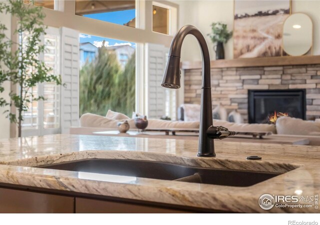 room details with a stone fireplace, a sink, and light stone countertops