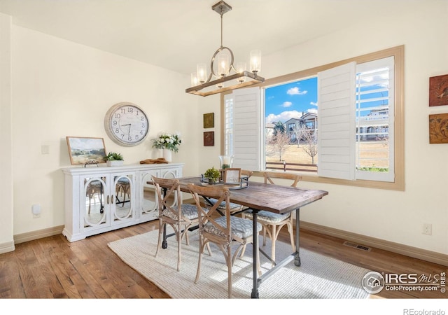 dining area featuring a chandelier, wood finished floors, visible vents, and baseboards