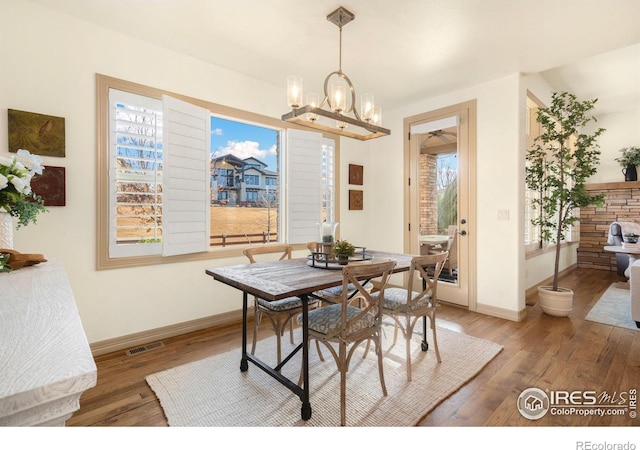 dining room featuring a chandelier, light wood-type flooring, visible vents, and baseboards