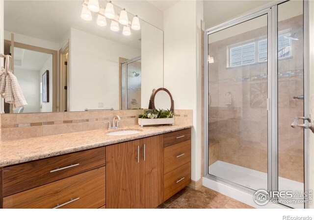 bathroom with tasteful backsplash, tile patterned flooring, a shower stall, and vanity