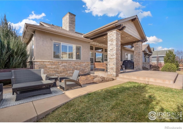 rear view of house with a patio, stone siding, a chimney, a yard, and stucco siding