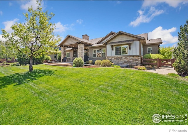 6774 Grand Park Dr, Timnath, CO 80547 - rear view of house with stone siding, a chimney, and board and batten siding