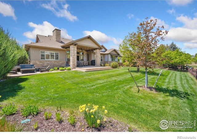 6774 Grand Park Dr, Timnath, CO 80547 - back of house with stone siding, a patio, and a chimney