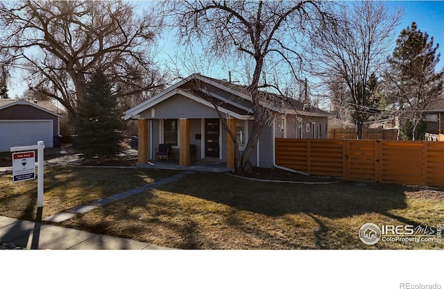 view of front of house featuring an outbuilding, a front lawn, a detached garage, and fence