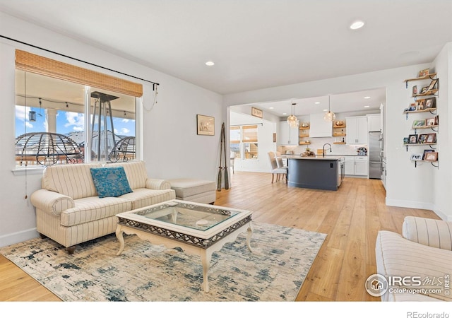 living room with recessed lighting, light wood-style flooring, and baseboards