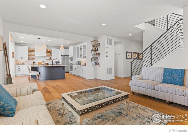 living area with light wood-type flooring, stairs, visible vents, and recessed lighting