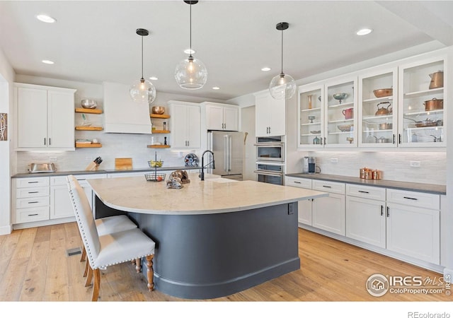 kitchen with premium range hood, light wood-style floors, white cabinets, appliances with stainless steel finishes, and open shelves