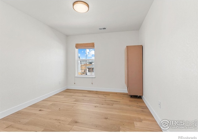 unfurnished room featuring light wood-type flooring, baseboards, and visible vents