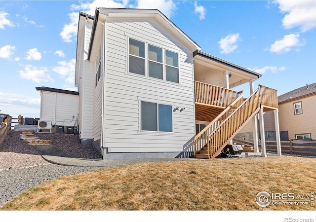 rear view of property with fence, stairway, and a yard