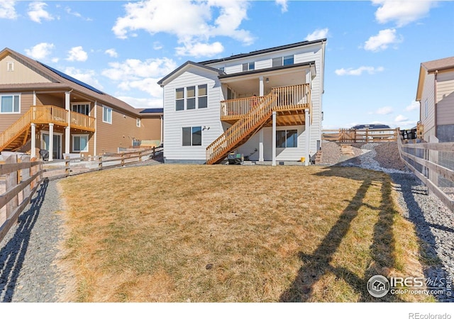 back of property with a deck, a fenced backyard, a yard, and stairway