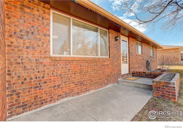 doorway to property featuring a patio area and brick siding