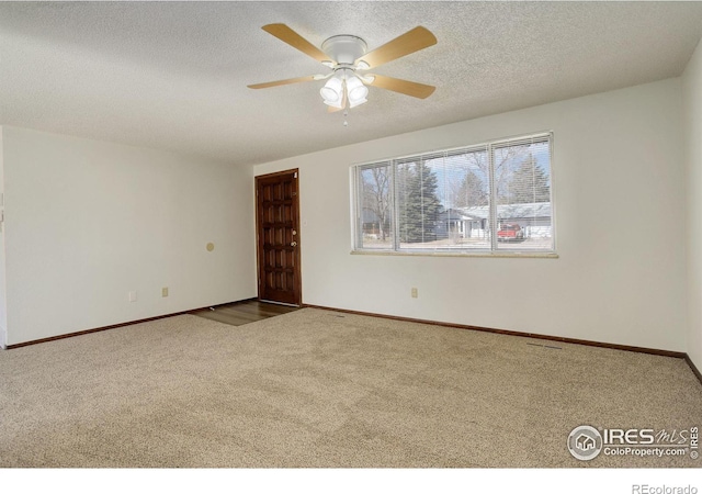 empty room with a textured ceiling, ceiling fan, carpet flooring, and baseboards