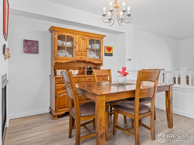 dining space with a chandelier, light wood-style flooring, and baseboards