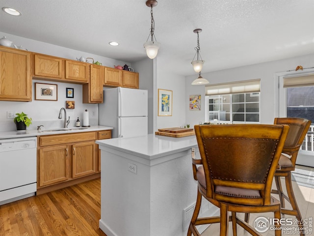 kitchen featuring white appliances, a sink, light wood-style floors, light countertops, and pendant lighting