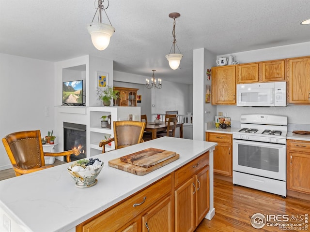 kitchen with light countertops, white appliances, a glass covered fireplace, and light wood-style floors