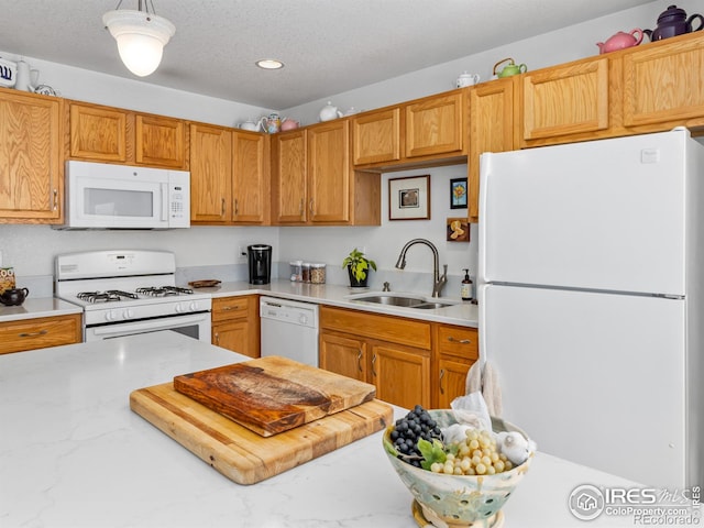 kitchen featuring white appliances, light countertops, and a sink