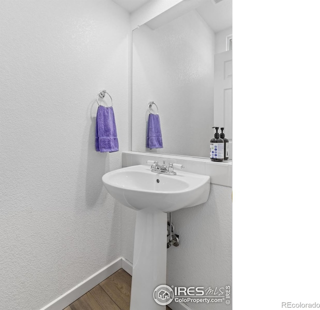 bathroom with a textured wall, wood finished floors, and baseboards