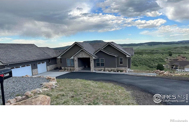 view of front of home with a garage, driveway, and stone siding