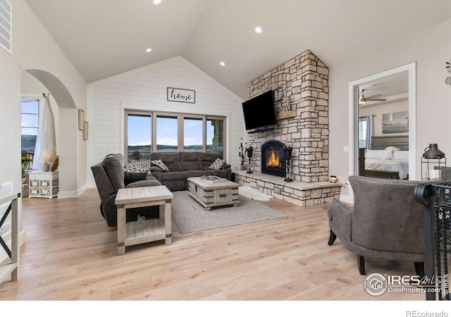 living area with arched walkways, wood finished floors, a wealth of natural light, and a fireplace