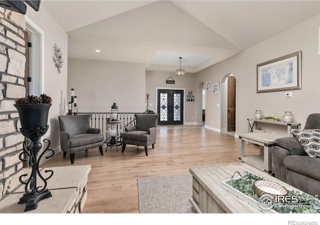 living area featuring arched walkways, recessed lighting, lofted ceiling, and light wood-style floors