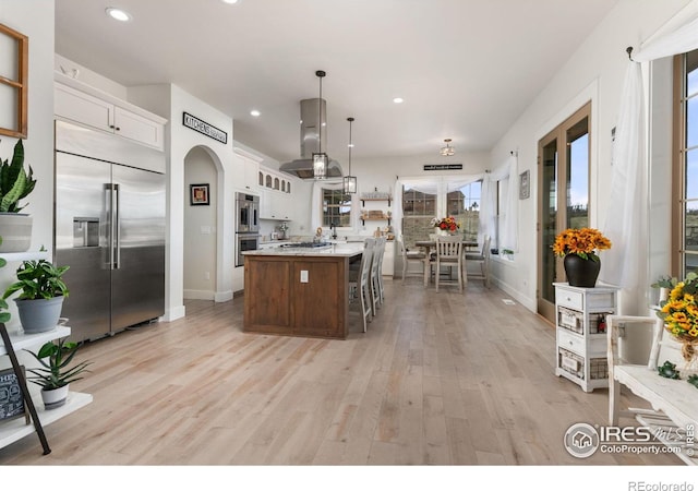 kitchen with light wood-style floors, baseboards, light countertops, white cabinetry, and stainless steel appliances