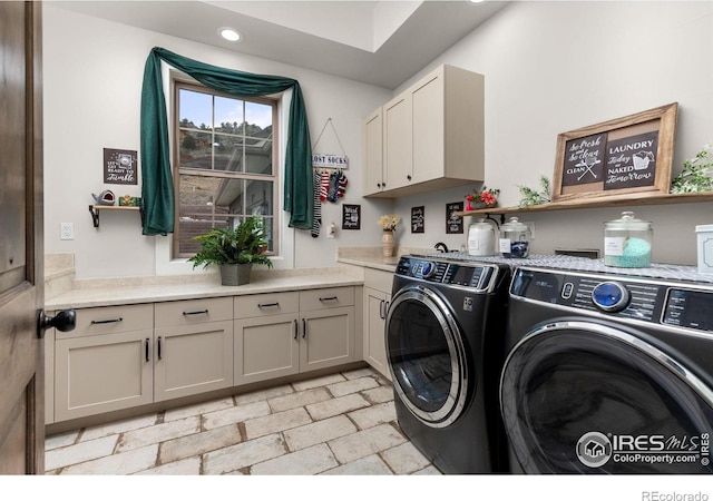 clothes washing area featuring stone finish floor, recessed lighting, cabinet space, and washer and clothes dryer