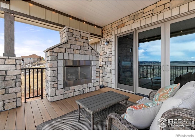 wooden terrace with an outdoor living space with a fireplace