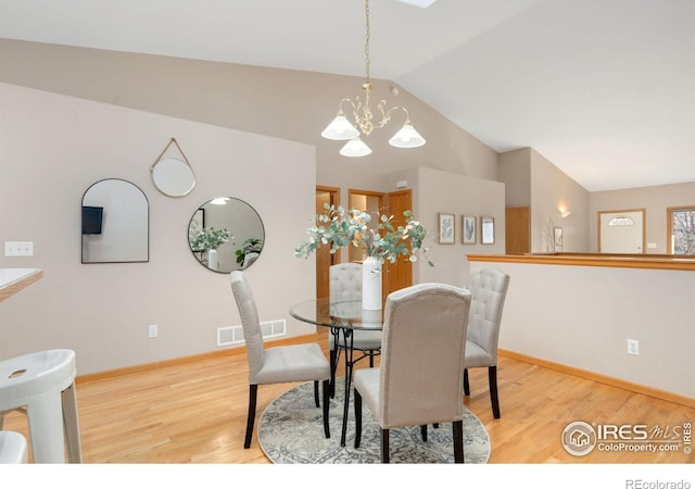 dining room with a notable chandelier, visible vents, baseboards, vaulted ceiling, and light wood-style floors