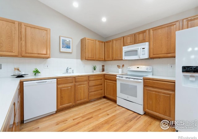 kitchen featuring lofted ceiling, light wood-style flooring, white appliances, a sink, and tasteful backsplash