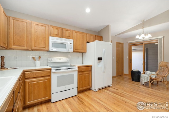 kitchen with light wood finished floors, white appliances, a chandelier, and decorative backsplash