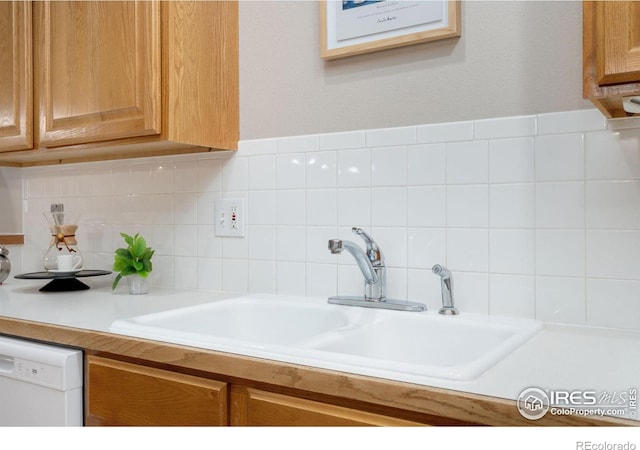 kitchen with light countertops, white dishwasher, backsplash, and a sink