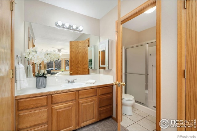 bathroom with toilet, a stall shower, tile patterned flooring, and vanity