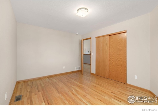 unfurnished bedroom with a closet, visible vents, and light wood-style floors