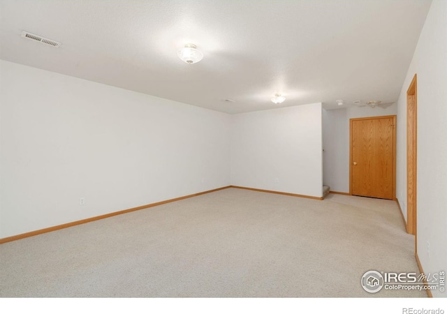 unfurnished room with baseboards, visible vents, and light colored carpet