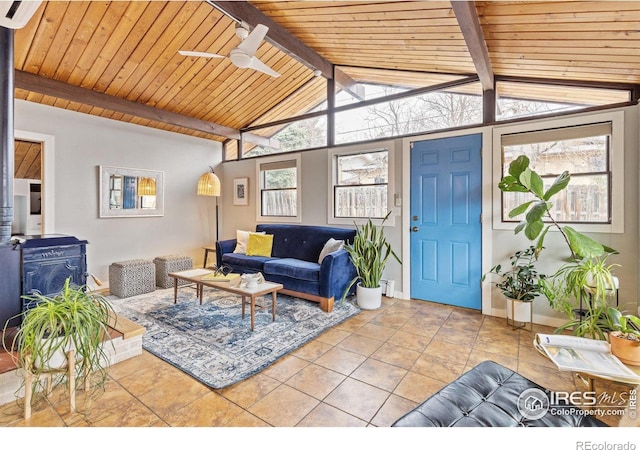 living area featuring vaulted ceiling with beams, a ceiling fan, a wood stove, wood ceiling, and tile patterned flooring