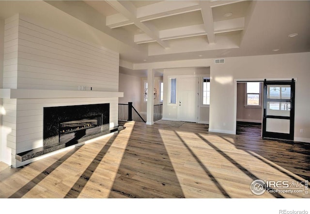 unfurnished living room featuring visible vents, hardwood / wood-style floors, coffered ceiling, beamed ceiling, and baseboards