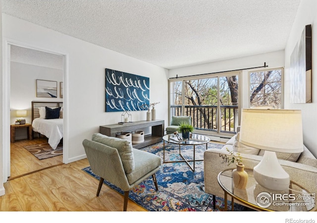 living area with a textured ceiling, baseboards, and wood finished floors