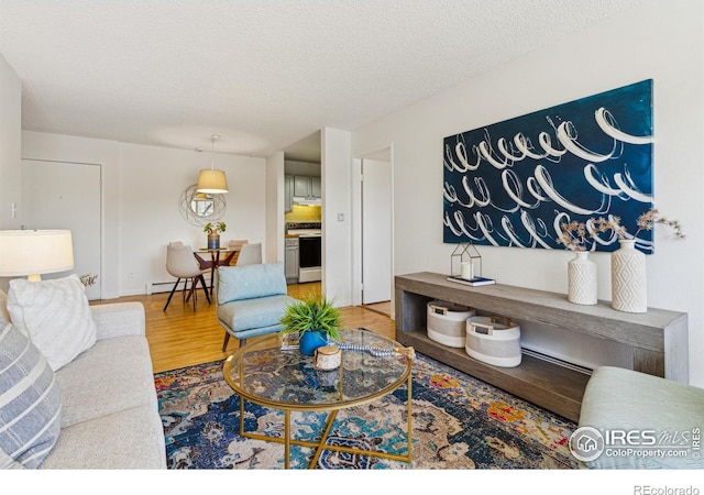 living room featuring a textured ceiling, a baseboard radiator, and wood finished floors