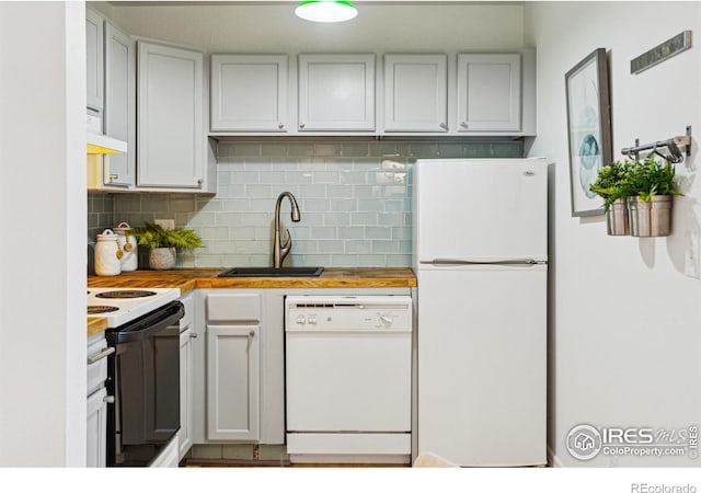 kitchen with white appliances, wood counters, decorative backsplash, and a sink