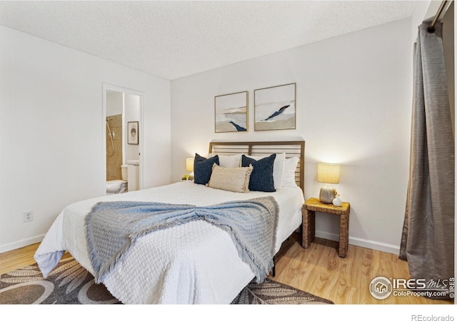 bedroom featuring a textured ceiling, baseboards, and wood finished floors