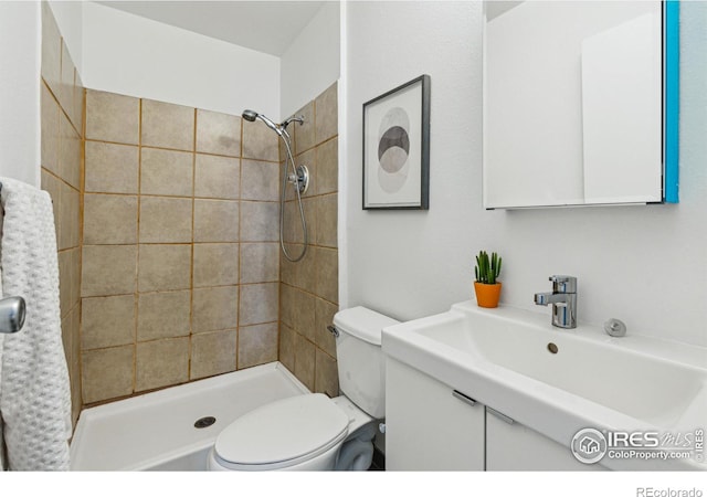 full bath with tiled shower, vanity, and toilet