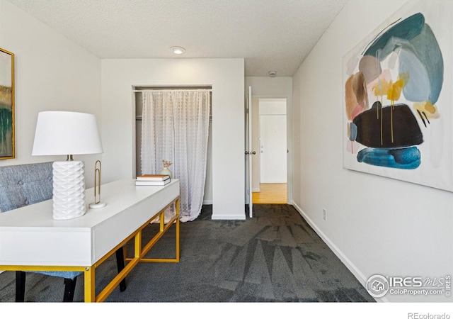 home office featuring a textured ceiling, carpet flooring, and baseboards