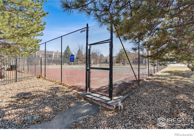 view of tennis court featuring a gate and fence