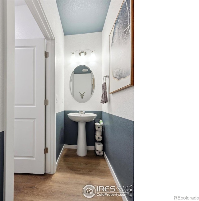 bathroom featuring a textured ceiling, wood finished floors, and baseboards