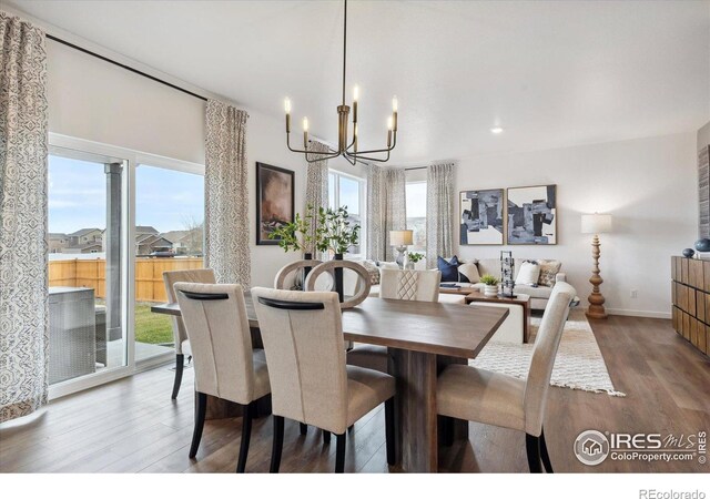 dining room featuring baseboards, wood finished floors, and a notable chandelier