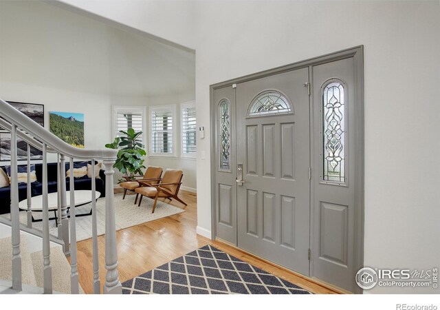 entrance foyer featuring stairs, high vaulted ceiling, and wood finished floors